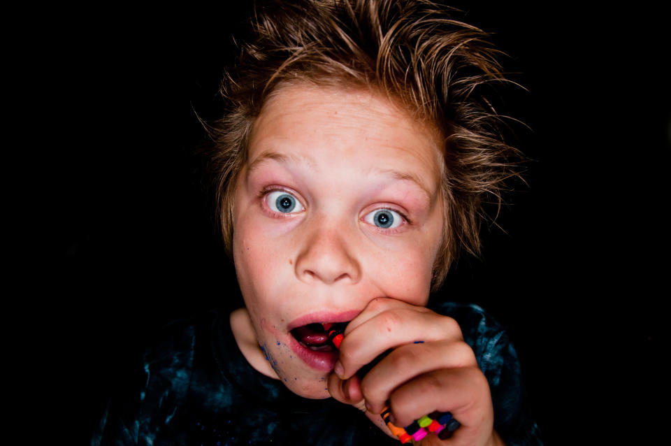 A young kid eating crayons