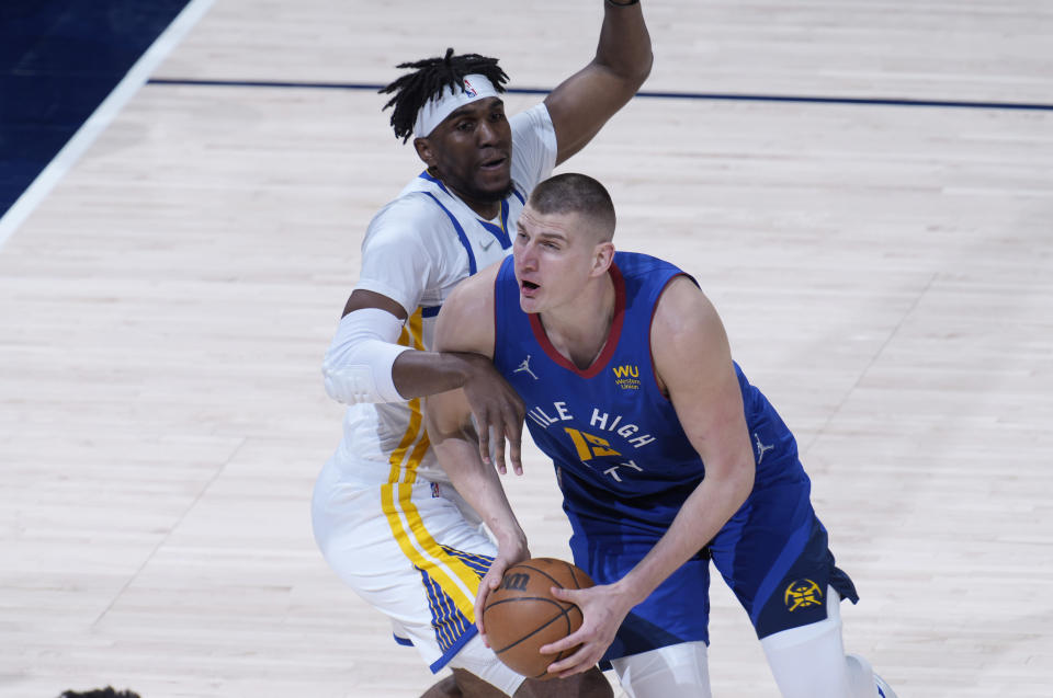 Denver Nuggets center Nikola Jokic, right, drives the lane as Golden State Warriors center Kevon Looney defends in the first half of Game 3 of an NBA basketball first-round Western Conference playoff series Thursday, April 21, 2022, in Denver. (AP Photo/David Zalubowski)