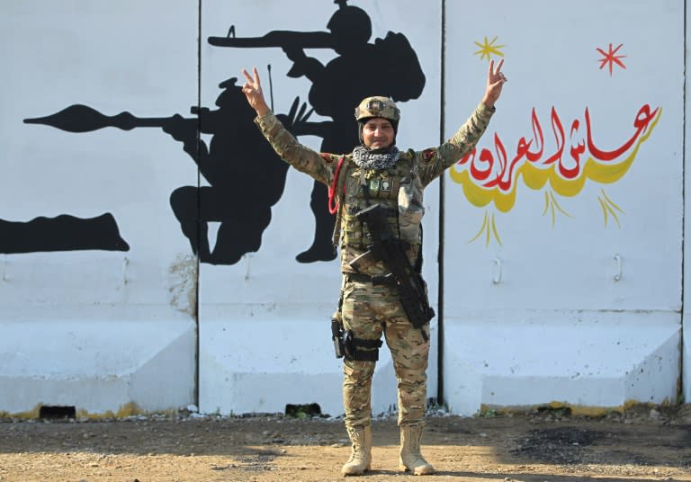 A member of Iraq's Rapid Response military unit poses in front of a mural glorifying Iraqi forces