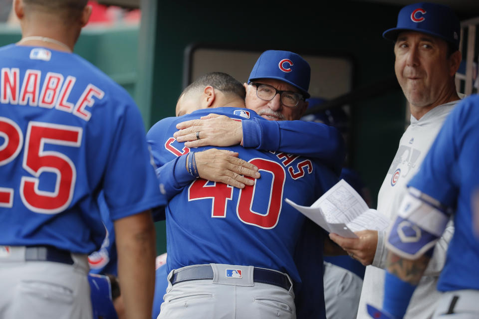 Chicago Cubs manager Joe Maddon, center right, hugs catcher Willson Contreras (40) before the team's baseball game against the Cincinnati Reds, Tuesday, May 14, 2019, in Cincinnati. (AP Photo/John Minchillo)