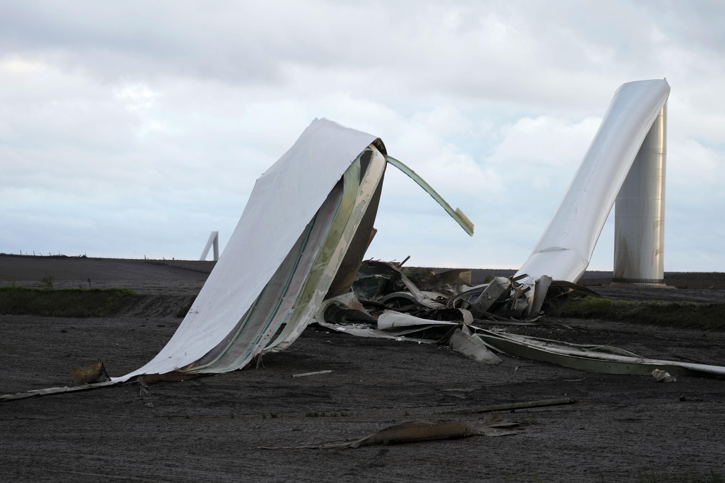 The remains of a tornado-damaged wind turbine touch the ground in a field on Tuesday near Prescott, Iowa.