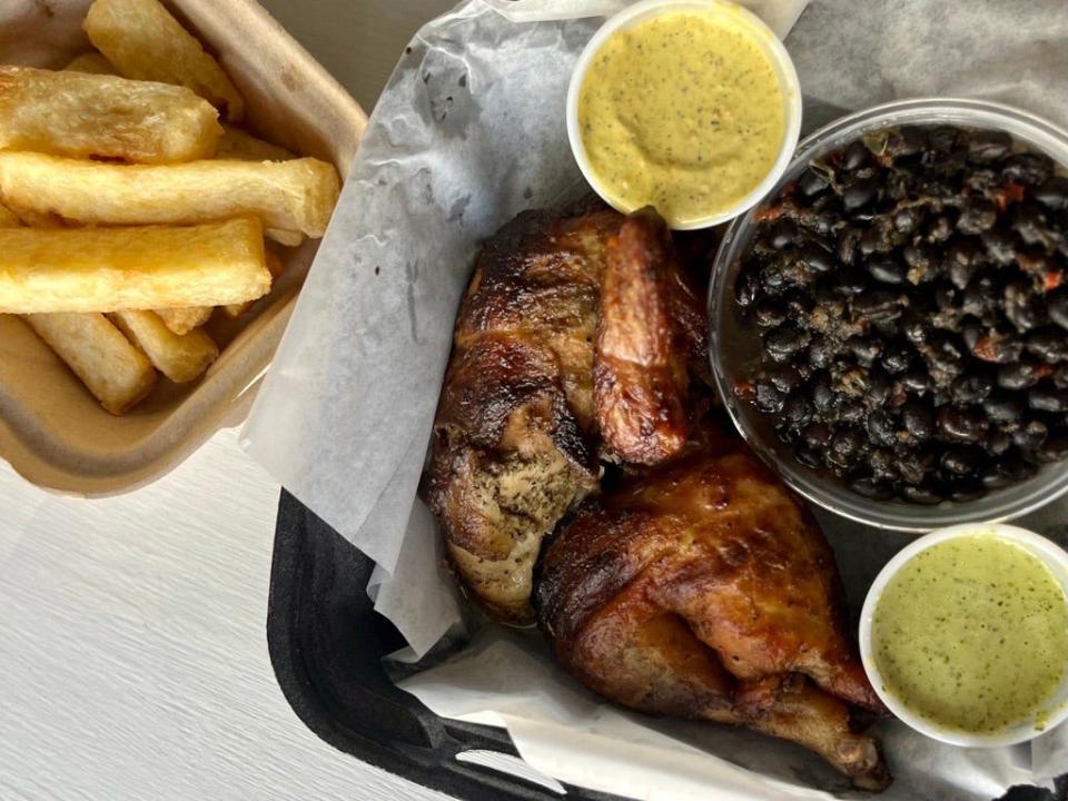 Peruvian-style rotisserie chicken, yuca fries and black beans and rice with green and yellow sauces from Pollo & Papas, 7071 Raeford Road, Fayetteville.