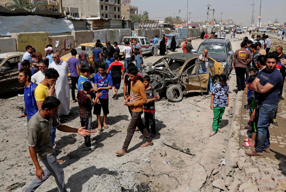Civilians inspect the site of a car bomb attack in Baghdad's Sadr City neighborhood, Iraq, Wednesday, April 9, 2014. Iraqi officials say a series of car bombs has hit several mostly Shiite neighborhoods in Baghdad, killed and wounded scores of people, according to Iraqi officials. (AP Photo/Karim Kadim)