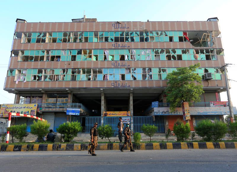 Afghan security forces walk past a building where the attackers of a jail compound were hiding following the attack, in Jalalabad