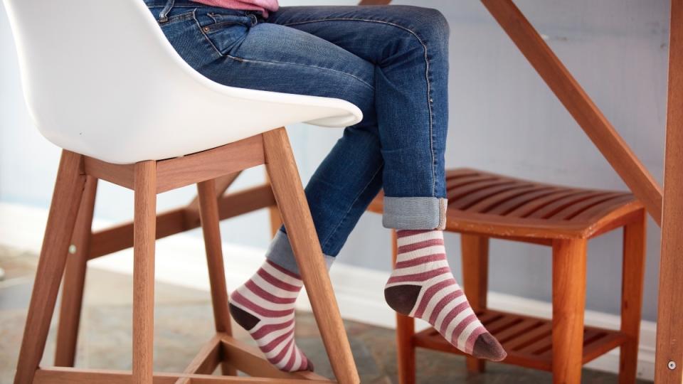 A close up of a woman in jeans wearing pink and red striped compression socks