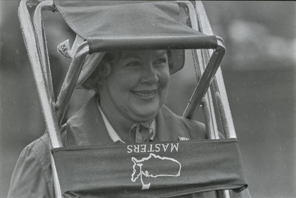 A person uses a chair to shield her head from the rain at the Augusta National Golf Course during the 1984 Masters on April 9, 1984.