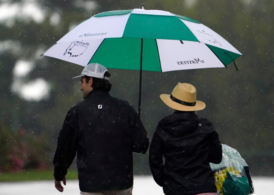 Patrons hold an umbrella and leave the course during a weather suspension during last year's Par 3 Contest at the Masters.