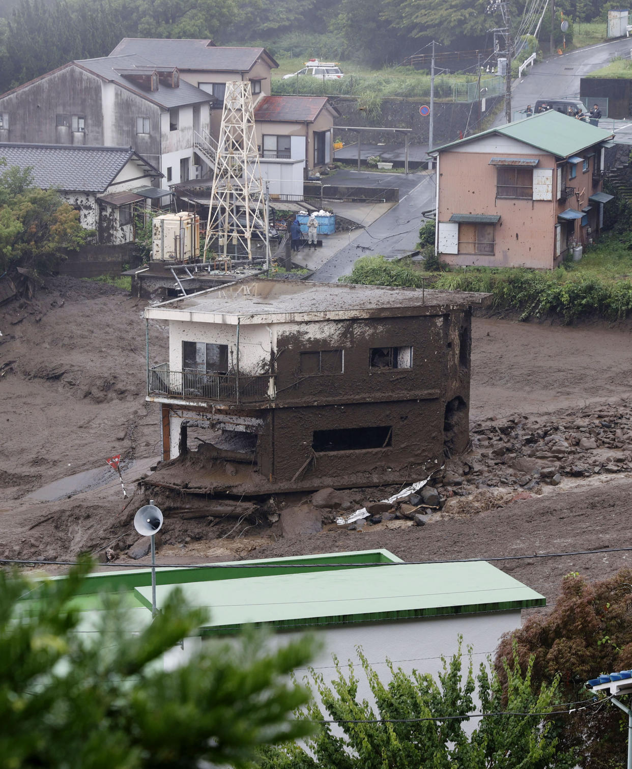 This photo shows buildings damaged by a mudslide at the Izusan district in Atami, west of Tokyo, Saturday, July 3, 2021, following heavy rains in the area. The mudslide carrying a deluge of black water and debris crashed into rows of houses in the town following heavy rains on Saturday, leaving multiple people missing, officials said. (Kyodo News via AP)