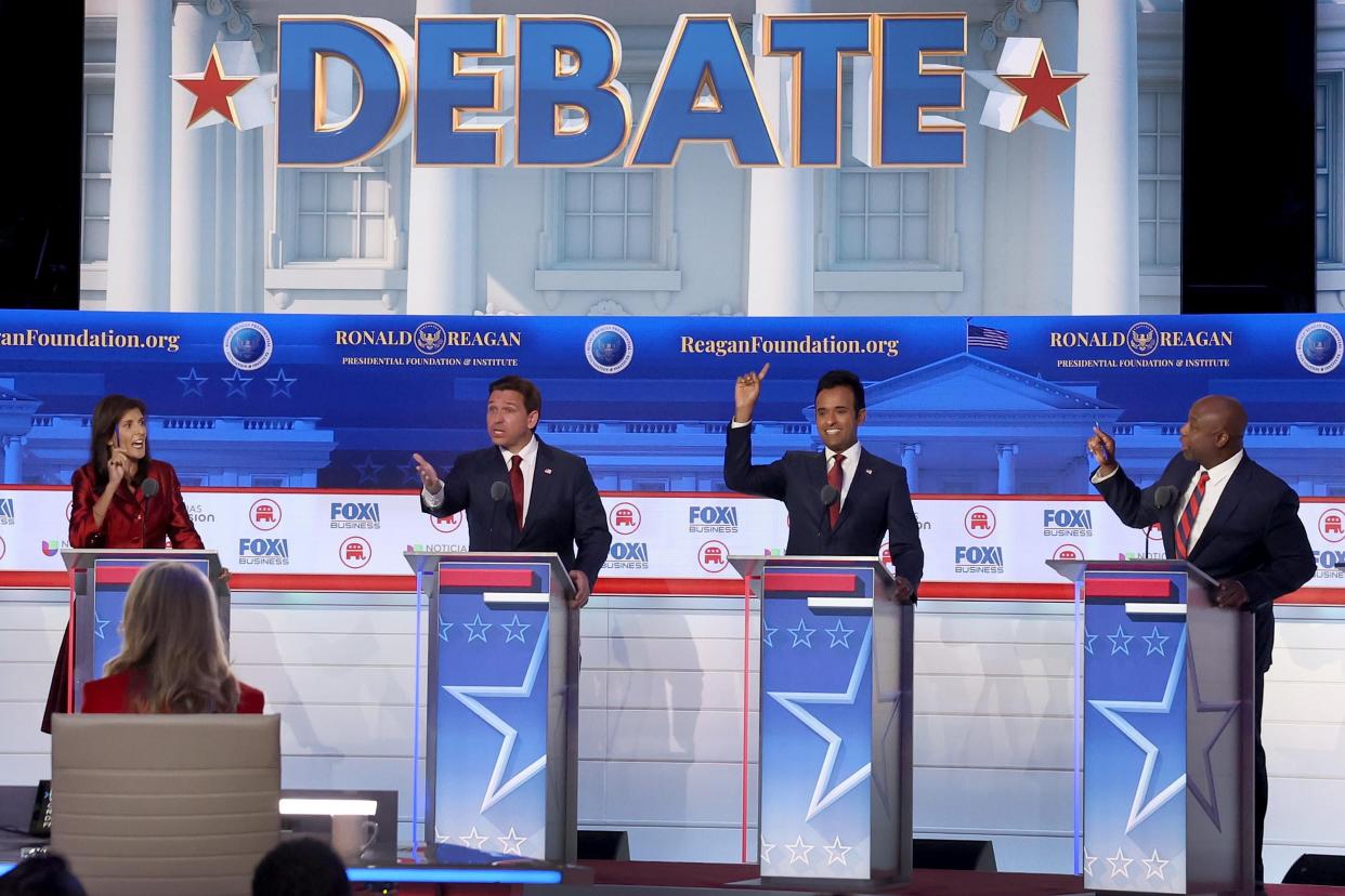 The four candidates gesture and yell at each other onstage