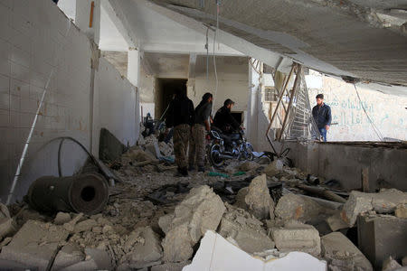 Men salvage a motorbike amid the damage inside a medical point at a site hit by airstrikes on Tuesday, in the town of Khan Sheikhoun in rebel-held Idlib, Syria April 5, 2017. REUTERS/Ammar Abdullah