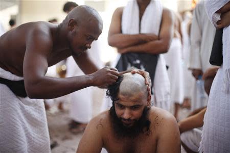 A Muslim pilgrim has his head shaved after casting pebbles at a pillar that symbolizes Satan during the annual haj pilgrimage, on the first day of Eid al-Adha in Mina, near the holy city of Mecca October 15, 2013. REUTERS/Ibraheem Abu Mustafa