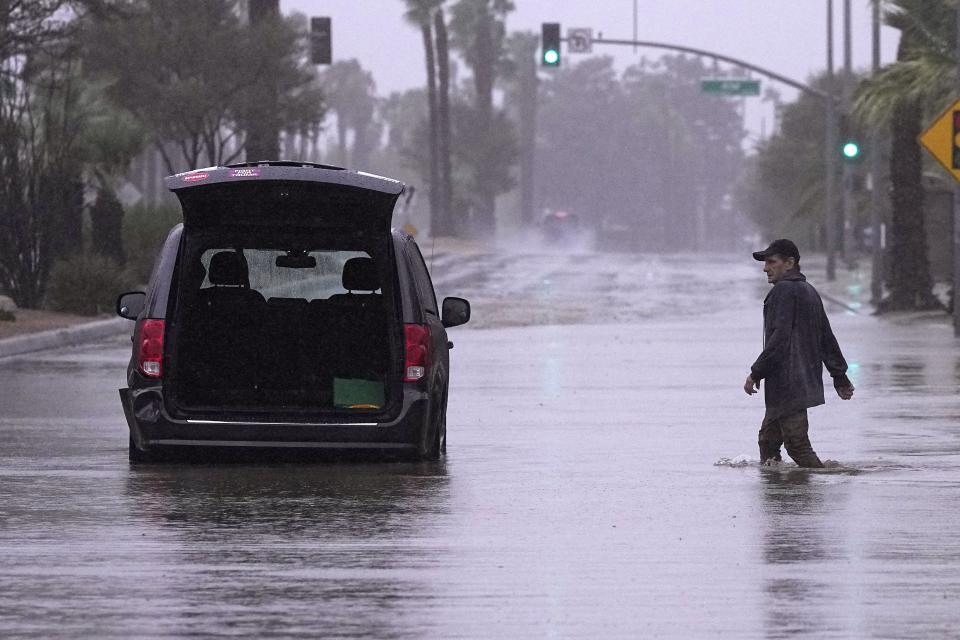 A motorist walks out to remove belongings from his vehicle after becoming stuck in a flooded street, Sunday, Aug. 20, 2023, in Palm Desert, Calif. Forecasters said Tropical Storm Hilary was the first tropical storm to hit Southern California in 84 years, bringing the potential for flash floods, mudslides, isolated tornadoes, high winds and power outages. (AP Photo/Mark J. Terrill)