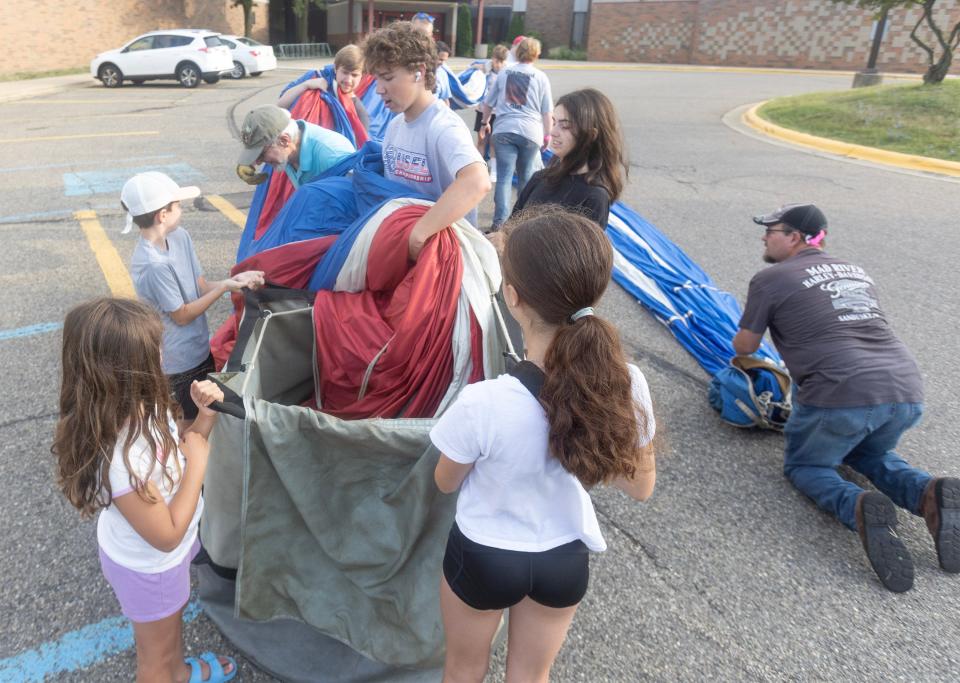 North Canton neighbors, including the Faye family, help the Diamond Girl balloon crew piloted by Ken Kus pack the envelope away after landing Friday morning near the North Canton High School parking lot. The balloon is participating in the 2023 Balloon Classic.