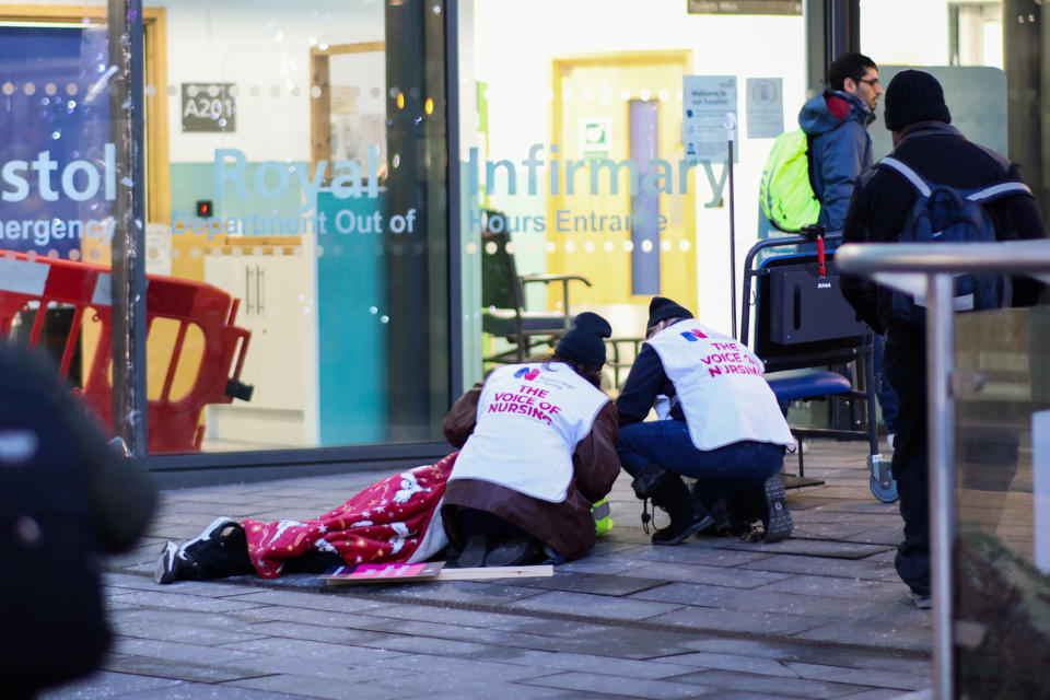 Royal College of Nursing members help a man who collapsed outside of Bristol Royal Infirmary. (SWNS)