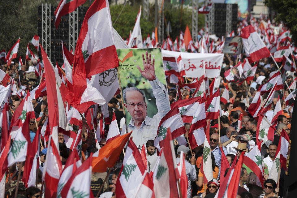 Supporters of Lebanese President Michel Aoun carry pictures of him and Lebanese flags during a protest near the presidential palace in the Beirut suburb of Baabda, Lebanon, Sunday, Nov. 3, 2019. Thousands of people are marching to show their support for Aoun and his proposed political reforms that come after more than two weeks of widespread anti-government demonstrations. (AP Photo/Hassan Ammar)