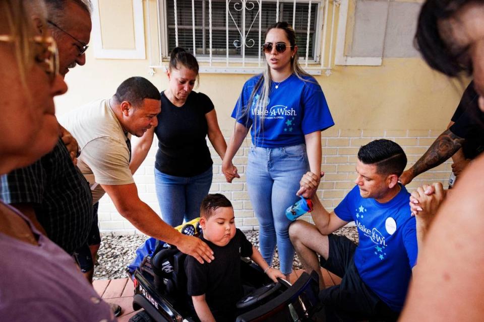 Orlin Funez, left, evangelist, prays over Franco Bernal, 6, who is battling childhood leukemia, center, with his parents Wendy, back, and Jorge, right, and other family members after Bernal’s Wish Reveal on Thursday, July 18, 2024, with Make-A-Wish and City of Miami Police in Miami. Bernal loves the police and Disney World, and so they organized a parade to announce that his wish to go to Disney World is being granted next week.