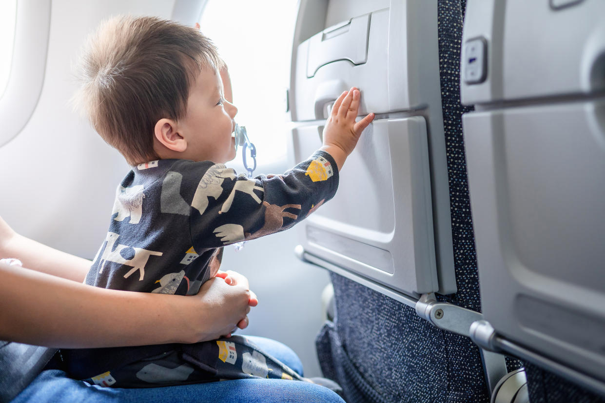 Baby sitzt im Flugzeug auf dem Schoß seiner Mutter