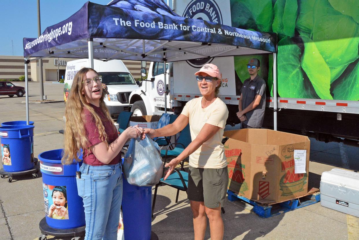 The Food Bank for Central and Northeast Missouri on Friday held a food drive to help fill pantries at middle and high schools in Boone County. Grace Reynolds, an Americorps VISTA for the food bank, hands off a bag of food outside the mall to volunteer Becky Bexten before starting her shift inside the mall, while food bank vehicle driver Gideon Rider watches on.