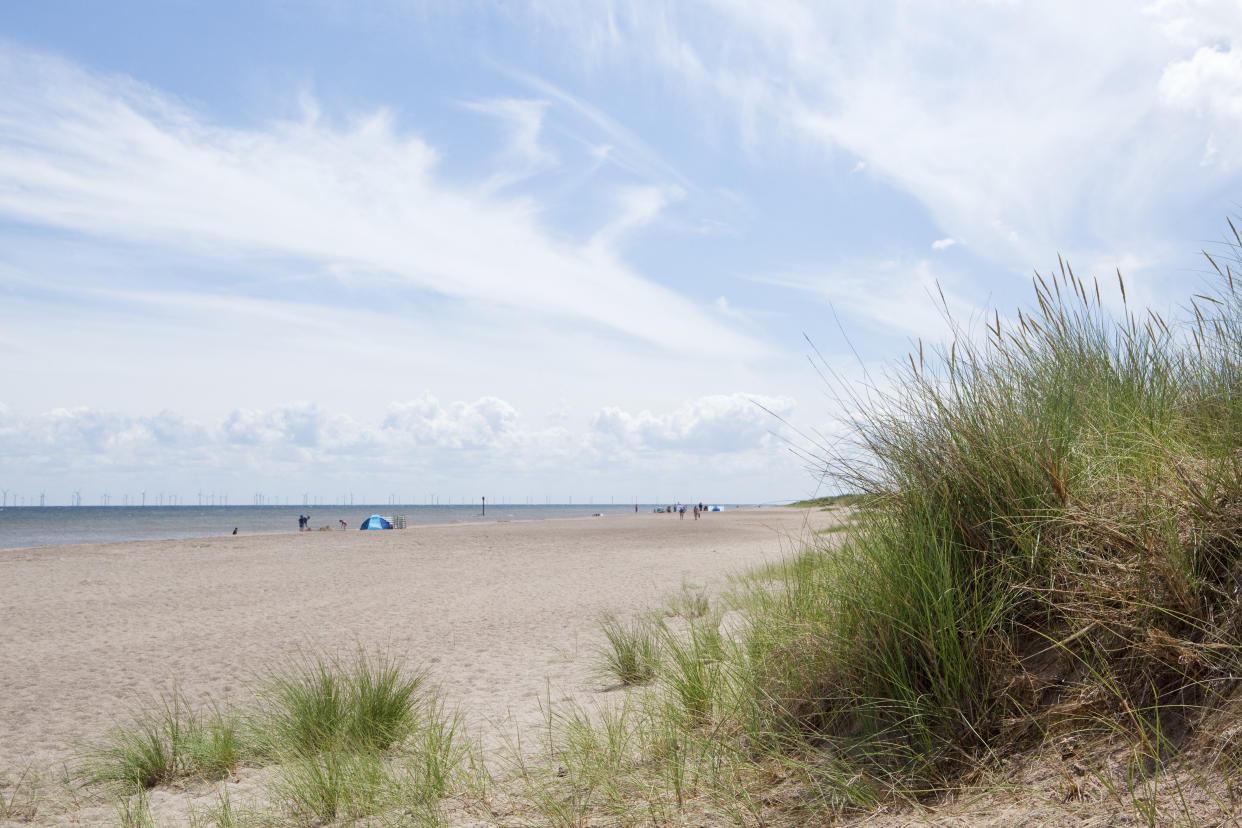 sand dunes, beach goers and wind farms in the distance at Anderby Creek, Lincolnshire, UK.