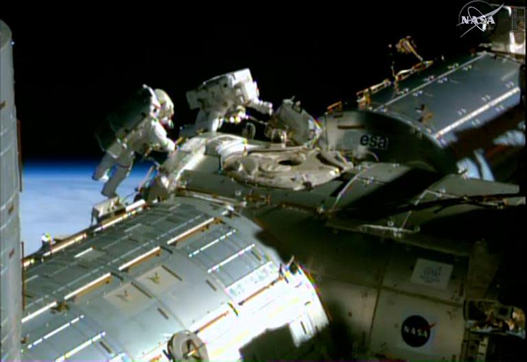 This February 21, 2015 NASA TV image shows astronauts Barry Wilmore (L) and Terry Virts during a spacewalk to lay cable on the International Space Station