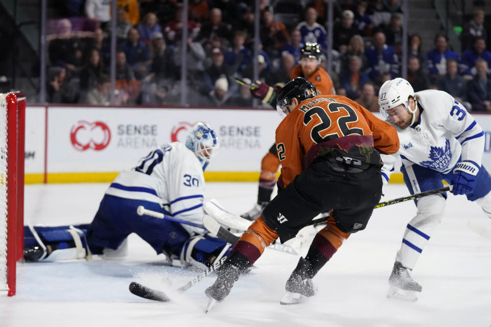 Arizona Coyotes center Jack McBain (22) beats Toronto Maple Leafs goaltender Matt Murray (30) and defenseman Timothy Liljegren (37) for a goal during the third period of an NHL hockey game in Tempe, Ariz., Thursday, Dec. 29, 2022. The Coyotes won 6-3. (AP Photo/Ross D. Franklin)