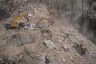 A damaged truck is covered with rocks and stones as earth movers dig through rubble of a collapsed tunnel in Ramban district, south of Srinagar, Indian controlled Kashmir, Friday, May 20, 2022. An official in Indian-controlled Kashmir said Friday that 10 workers were trapped after part of a road tunnel collapsed in the Himalayan region. (AP Photo/Dar Yasin)