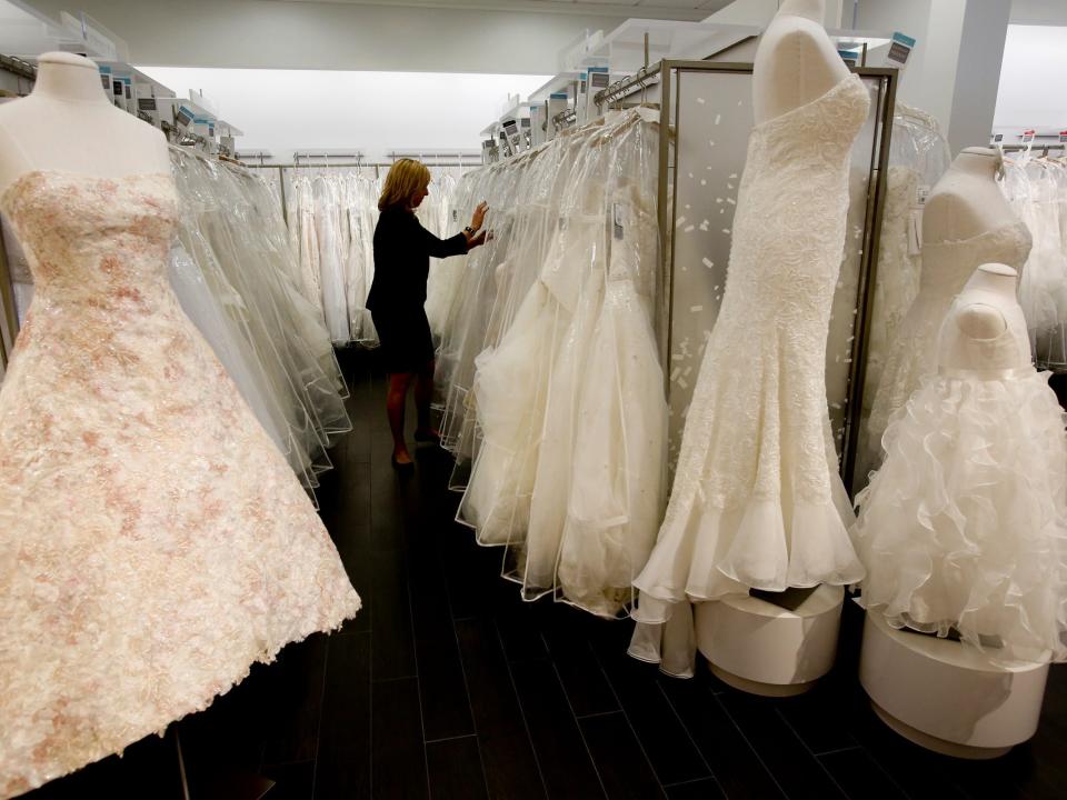 Woman looks through wedding gowns on racks at David's Bridal store