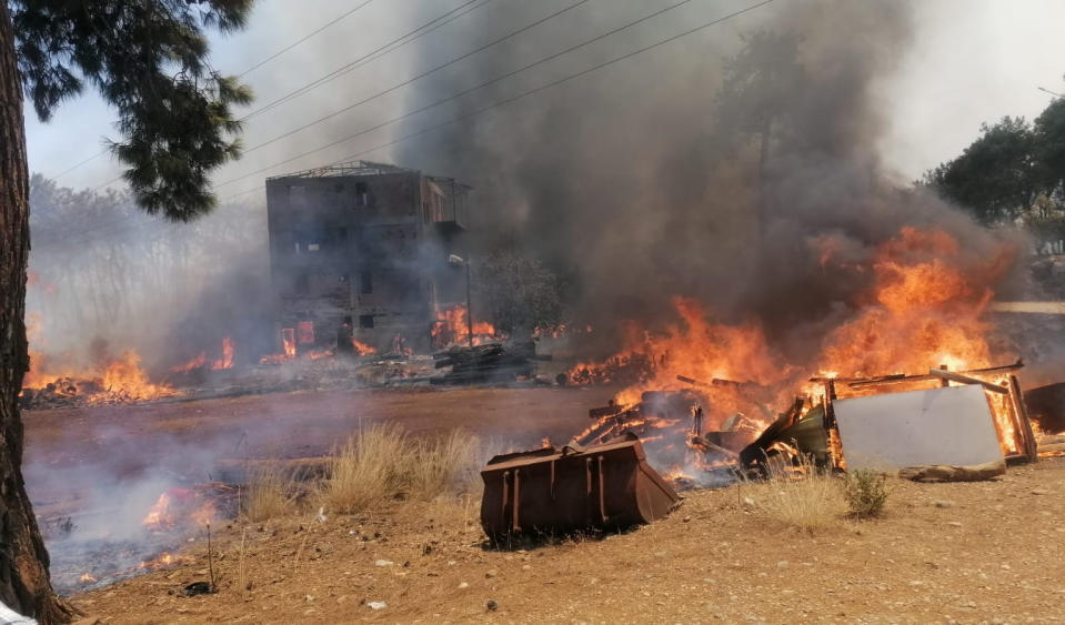 A wildfire fanned by strong winds engulfs a building near the Mediterranean coastal town of Manavgat, Antalya, Turkey, Wednesday, July 28, 2021. Authorities evacuated homes in Manavgat as a wildfire raged Wednesday through a forest. Gendarmerie forces helped move residents out of four neighborhoods in the town out of the fire's path as firefighters worked to control the blaze, the Manavgat district governor Mustafa Yigit told the state-run Anadolu Agency. (Arif Kaplan/IHA via AP)