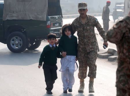 A soldier escorts schoolchildren after they were rescued from from the Army Public School that is under attack by Taliban gunmen in Peshawar, December 16, 2014. REUTERS/Khuram Parvez