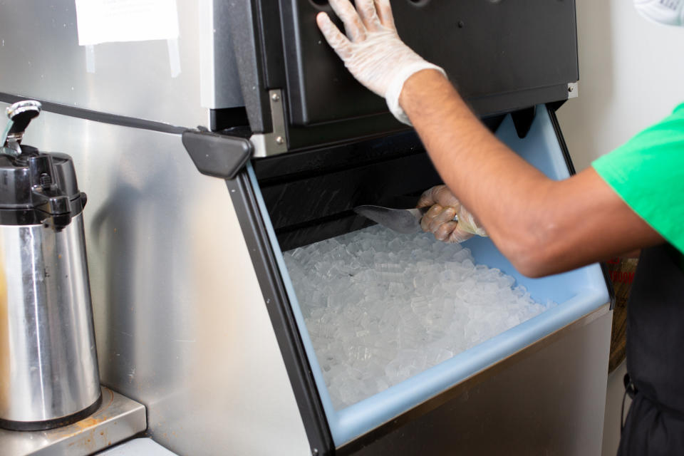 A person scooping ice from an ice maker