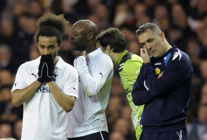 Bolton Wanderer's manager Owen Coyle (R) stands beside Tottenham players, Benoit Assou-Ekotto (L), William Gallas (2nd L) and Carlo Cudicini (2nd R) as Bolton's English midfielder Fabrice Muamba (not pictured) is treated by medical staff after collapsing during the English FA Cup quarter-final football match between Tottenham Hotspur and Bolton Wanderers at White Hart Lane in north London, England on March 17, 2012. The game was abandoned at half-time as Muamba was taken to hospital. RESTRICTED TO EDITORIAL USE. No use with unauthorized audio, video, data, fixture lists, club/league logos or “live” services. Online in-match use limited to 45 images, no video emulation. No use in betting, games or single club/league/player publications (Photo by Olly Greenwood/AFP/Getty Images)