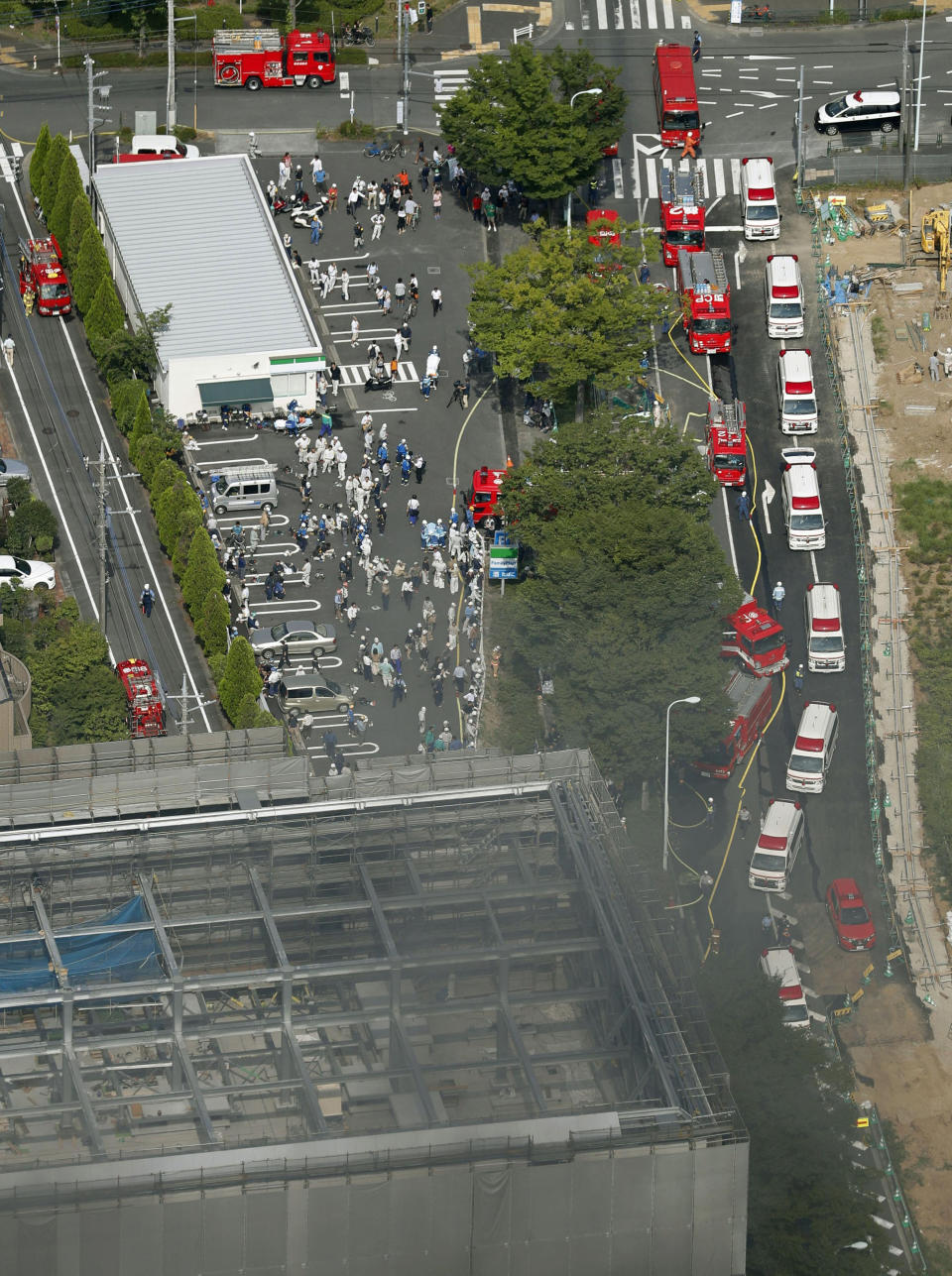 Fire trucks and ambulances line up near the site of a fire in Tama city, Tokyo's western suburbs, Thursday, July 26, 2018. The fire broke out Thursday afternoon, injuring a number of people at the building. (Kyodo News via AP)