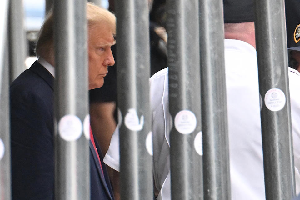Trump is seen through bars as he leaves the courthouse.