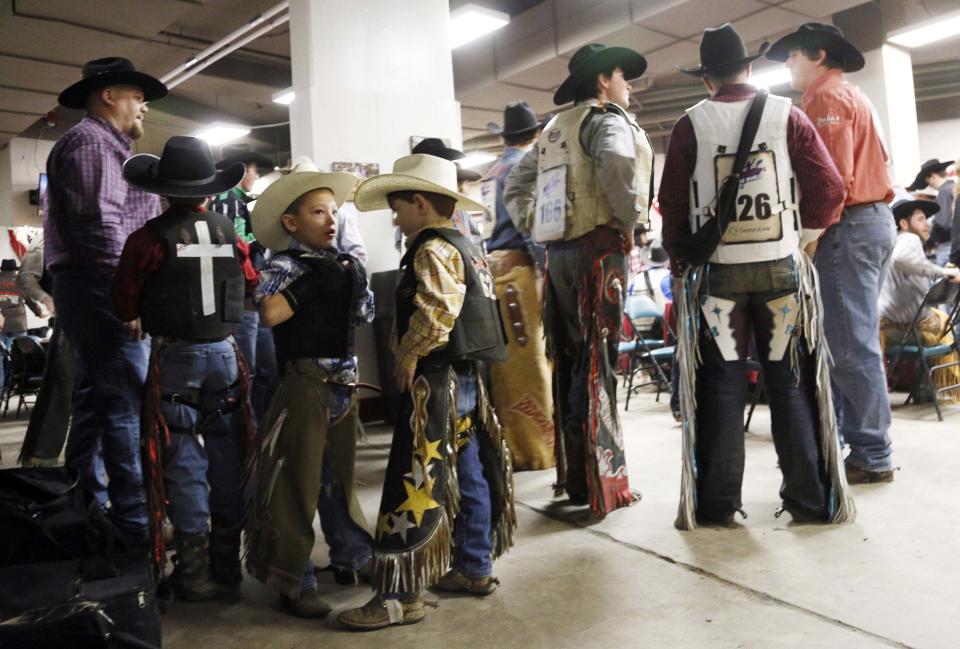 Mini bull riding competitors Gage Stimpson and Avery Speck and their adult counterparts talk before competing at the 108th National Western Stock Show in Denver