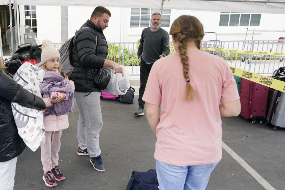 Phil Metzger, center in back, of the Christian church Calvary San Diego, talks with volunteers as they help Ukrainians arriving after crossing into the United States from Tijuana, Mexico, Friday, April 1, 2022, in Chula Vista, Calif. (AP Photo/Gregory Bull)