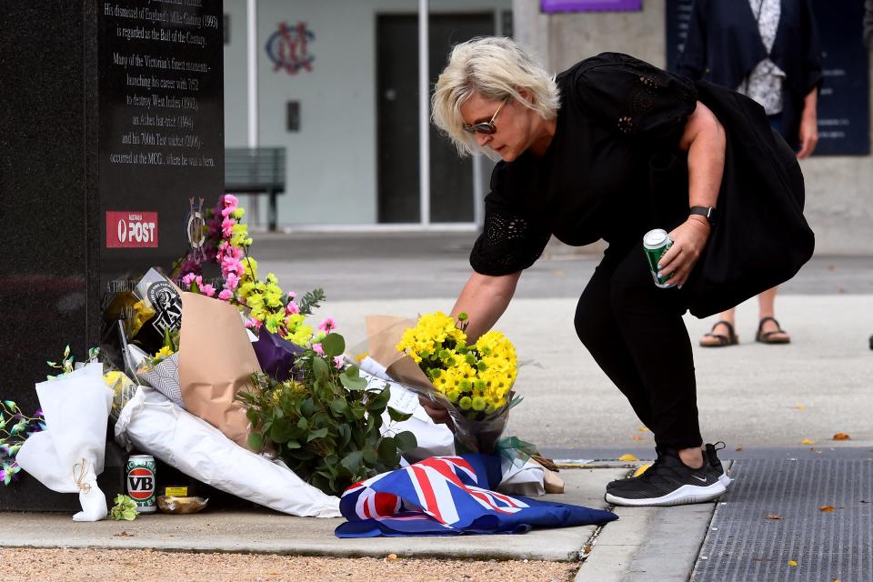 Seen here, A woman places flowers and a can of Victoria Bitter (VB) beer at a statue of Shane Warne at the MCG. 