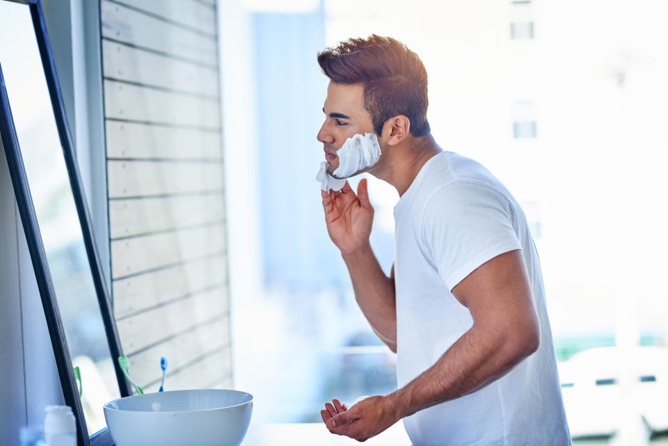 Shot of a handsome young man shaving his facial hair in the bathroom