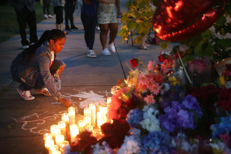 A woman chalks a message on May 15, 2022, at a makeshift memorial outside the Tops Friendly Markets store where a gunman killed 10 people in Buffalo, N.Y.