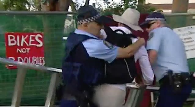 Two police officers wrestle to the ground a man holding a ladder on Wednesday. Photo: 7 News