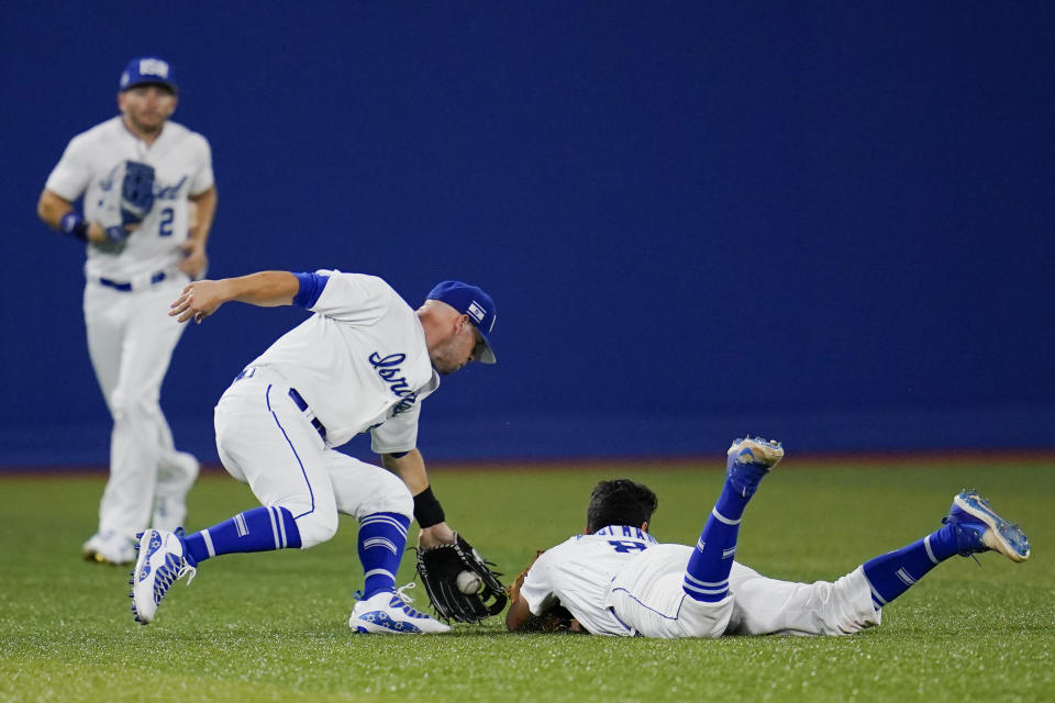 Israel's Scott Burcham, right, dives and cannot reach a ball picked up by Rob Paller, center, as Blake Gailen (2) looks on during a baseball game against the United States at the 2020 Summer Olympics, Friday, July 30, 2021, in Yokohama, Japan. (AP Photo/Sue Ogrocki)