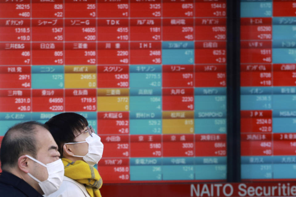 People walk by an electronic stock board of a securities firm in Tokyo, Wednesday, Jan. 12, 2022. Asian stock markets followed Wall Street higher on Wednesday after Federal Reserve chairman Jerome Powell said monetary policy would return to normal and interest rates might be raised earlier than planned.(AP Photo/Koji Sasahara)