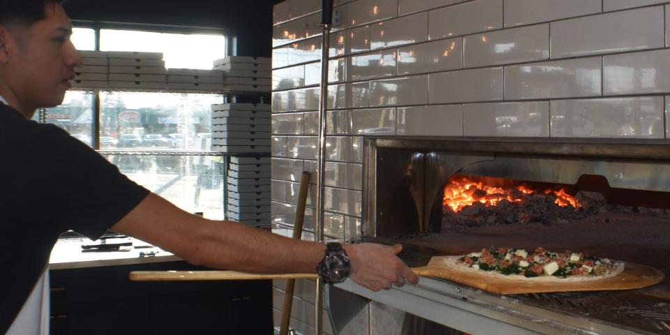 Andy Garcia slides a pizza into the oven at the new Cherry Hill location of Bricco Coal Fired Pizza.