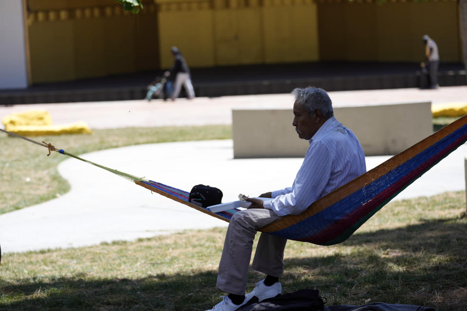 A man sits on a hammock under the shade of a tree as temperatures rise at MacArthur Park, Tuesday, July 11, 2023, in Los Angeles. (AP Photo/Marcio Jose Sanchez)