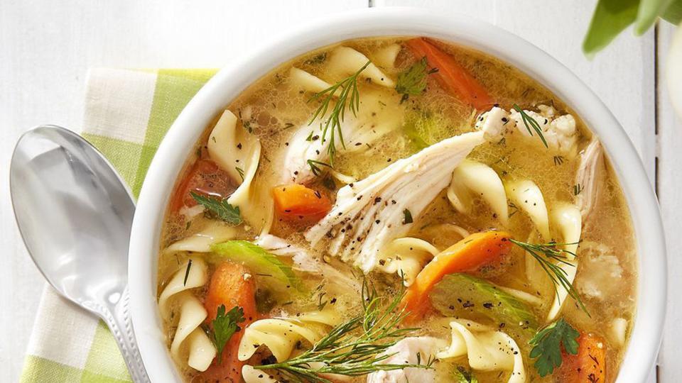 ultimate chicken noodle soup in a white bowl with a spoon