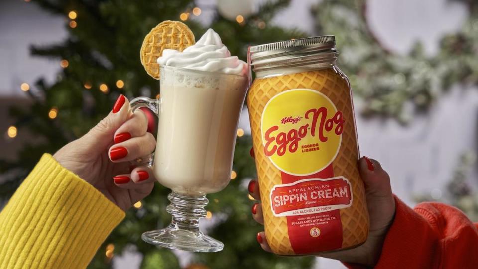 A toast between a glass of Eggo Nog with whipped cream and the bottle it comes in