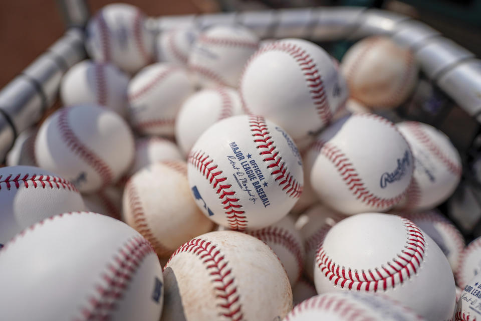 FILE - Baseballs are held in a basket on the field before a baseball game between the Cincinnati Reds and the Milwaukee Brewers in Cincinnati, Sunday, July 18, 2021. Major League Baseball is standardizing procedures for rubbing baseballs and their removal from humidors in an effort to establish more consistency amid complaints about slickness that followed the crackdown on sticky substances. MLB has been working on standards over the course of the season in response to feedback from players and sent a memorandum outlining the changes on Tuesday, June 21, 2022, to general managers, assistant GMs and clubhouse managers. (AP Photo/Bryan Woolston, File)