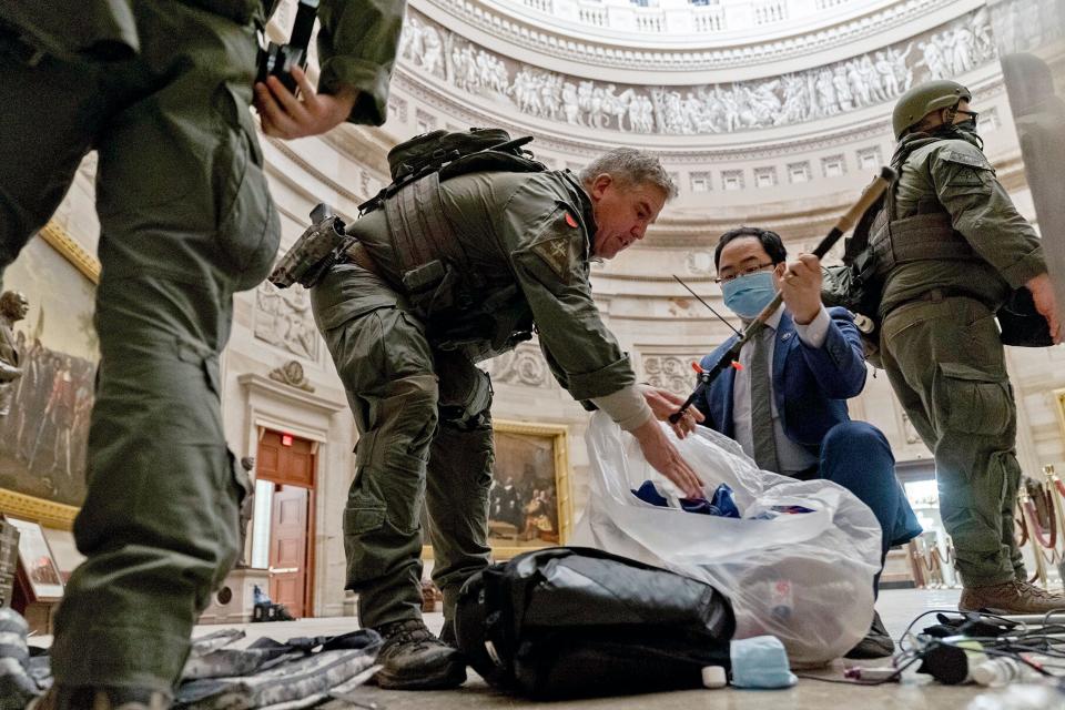 Rep. Andy Kim, D-N.J., helps ATF police officers clean up debris and personal belongings strewn across the floor of the Rotunda in the early morning hours of Thursday, Jan. 7, 2021, after protesters stormed the Capitol in Washington, on Wednesday.
