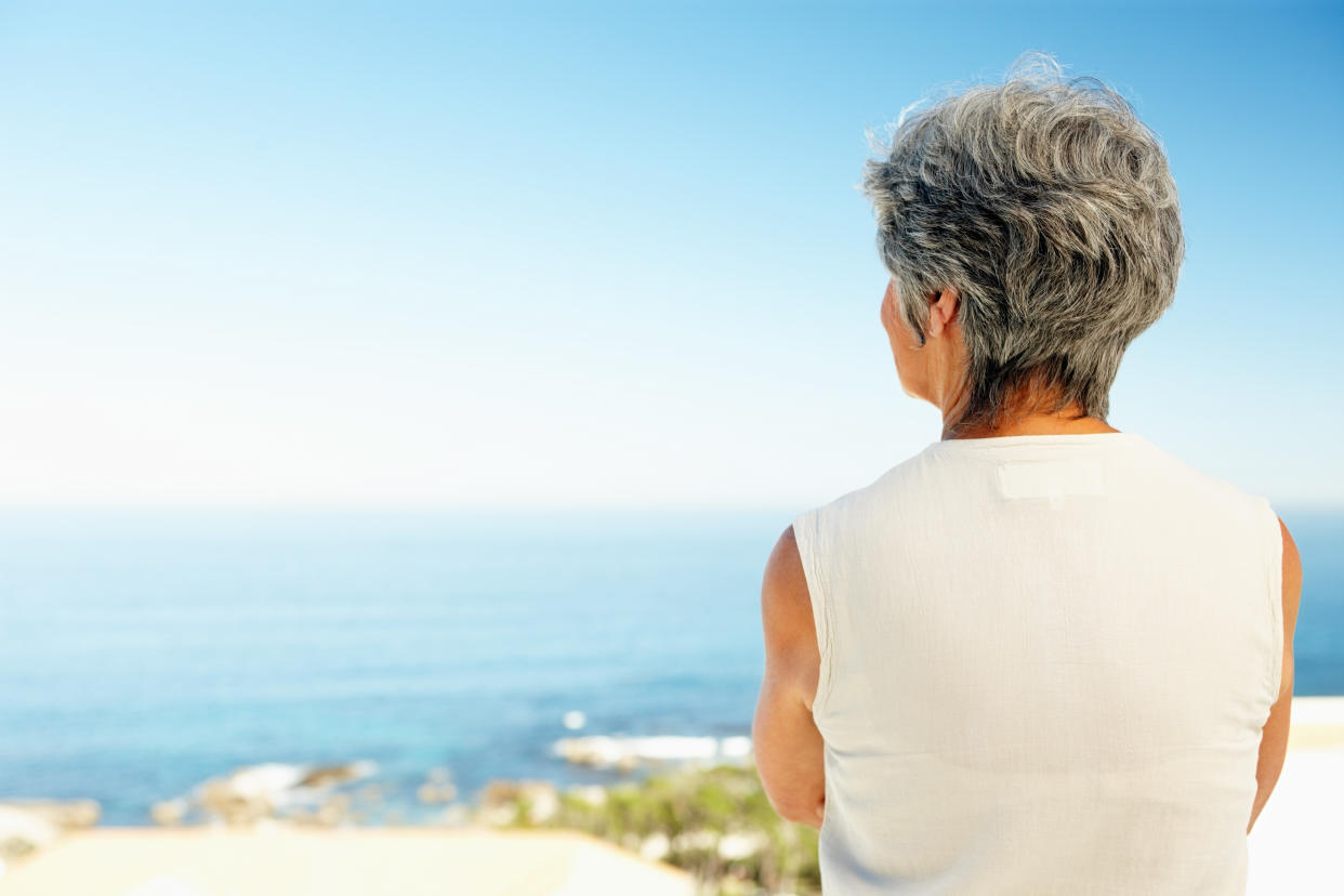 Rear view of senior woman in front of ocean - copyspace