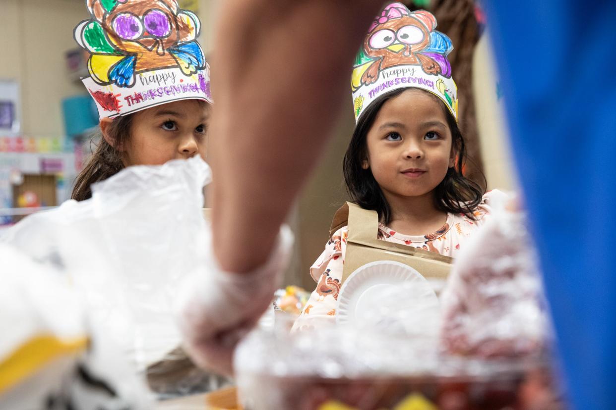 Grandparent volunteer Irma Villarreal dishes out food to pre-k students Daniella Gonzales, left, and Krizza Ybanez during Friendsgiving at Sam Houston Elementary on Thursday, Nov. 16, 2023, in Corpus Christi, Texas.