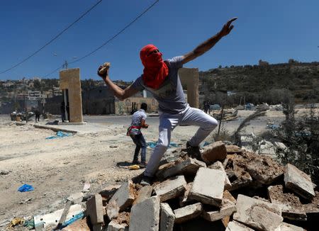 A Palestinian protester hurls stones towards Israeli troops during clashes in the West Bank village of Beita, near Nablus May 12, 2017. REUTERS/Mohamad Torokman